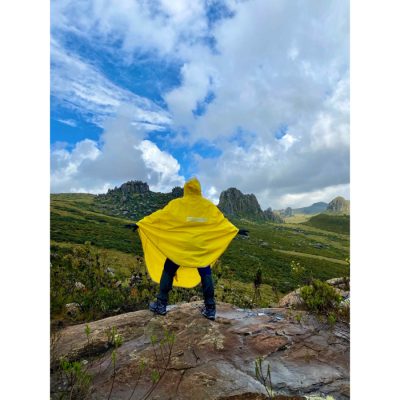 A hiker on a cliff in a yellow rain poncho